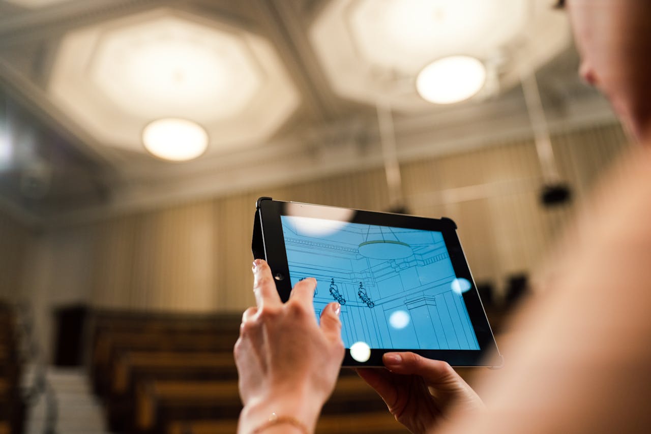 Woman engineer utilizing a digital tablet to design a ceiling in a modern auditorium setting.